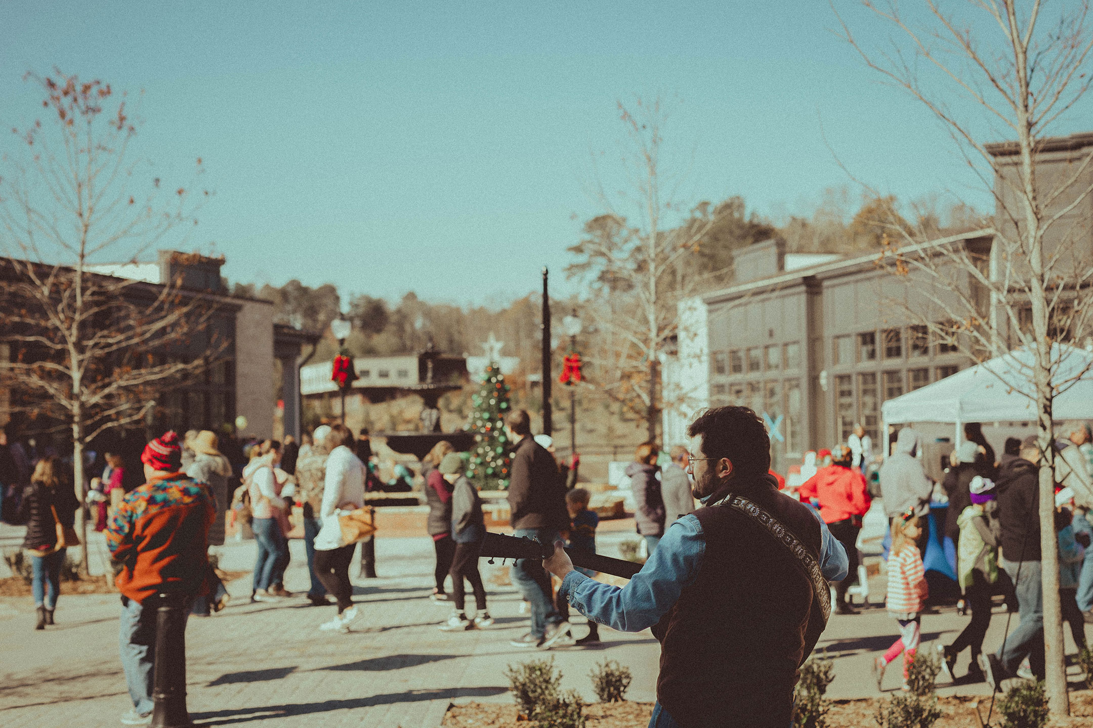 Man playing guitar at holiday event in outdoor plaza